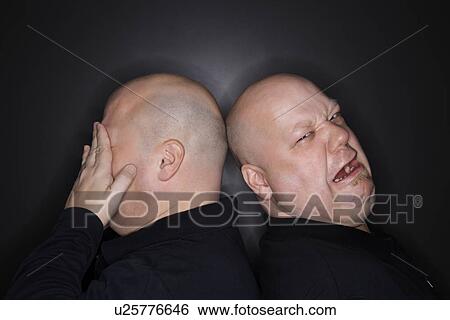 Bald identical twin men standing back to back with sad expressions View Large Photo Image Stock Photograph - Bald identical twin men standing back to back with sad expressions. Fotosearch