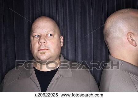 Stock Photography - Bald man looking to side at his identical twin. Fotosearch