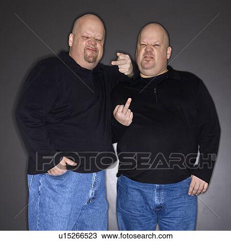 Bald mid adult identical twin men making obscene gesture at viewer. View Large Photo Image Stock Image - Bald mid adult identical twin men making obscene gesture at viewer.. Fotosearch
