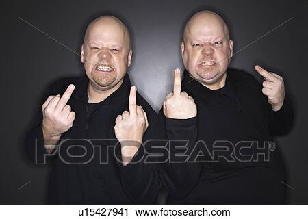 Stock Image - Bald mid adult identical twin men making obscene gesture at viewer.. Fotosearch