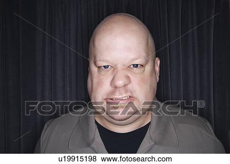 Stock Photo - Mid adult bald man looking at viewer with angry expression.. Fotosearch