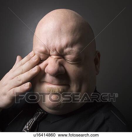 Mid adult bald man rubbing eye and making facial expression. View Large Photo Image Stock Image - Mid adult bald man rubbing eye and making facial expression.. Fotosearch