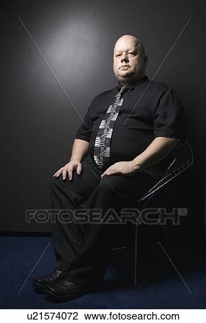 Stock Image - Mid adult bald man wearing necktie sitting and looking at viewer.. Fotosearch