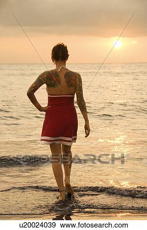 Attractive tattooed Caucasian woman on beach at sunset View Large Photo Image Stock Photo - Attractive tattooed Caucasian woman on beach at sunset . Fotosearch