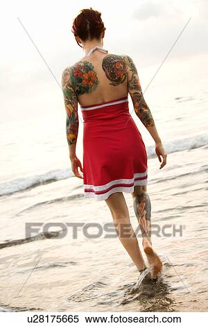 Stock Photography - Attractive tattooed Caucasian woman on beach . Fotosearch
