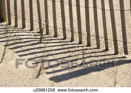 Stock Photo - Close-up of fence and shadows on beach Bald Head Island, North Carolina.. Fotosearch