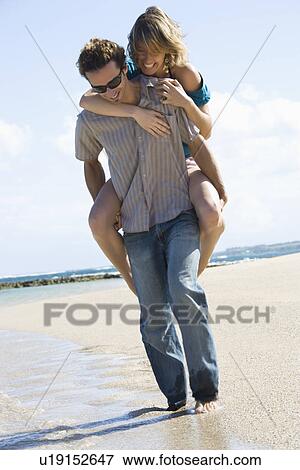 Man giving woman piggyback ride on beach View Large Photo Image Stock Photo - Man giving woman piggyback ride on beach . Fotosearch