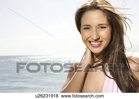 Stock Photo - Portrait of pretty young smiling Caucasian woman with long brown hair at beach . Fotosearch