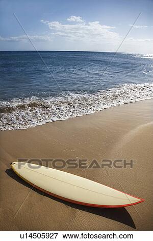 Stock Photo - Surfboard on sandy beach with ocean in background . Fotosearch