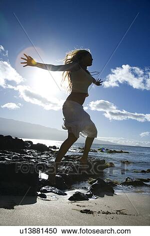 Stock Image - Young adult Asian Filipino female jumping on beach . Fotosearch