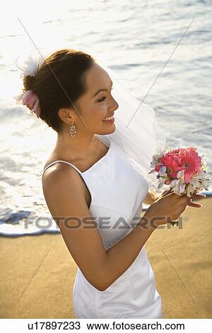 Young adult female bride holding bouquet on beach View Large Photo Image Stock Image - Young adult female bride holding bouquet on beach. Fotosearch