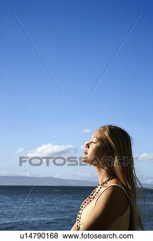 Stock Photo - Young adult female standing on beach . Fotosearch