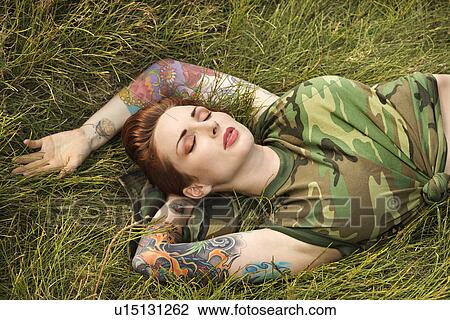 Attractive tattooed Caucasian woman in camouflage lying on grass View Large Photo Image Stock Image - Attractive tattooed Caucasian woman in camouflage lying on grass . Fotosearch
