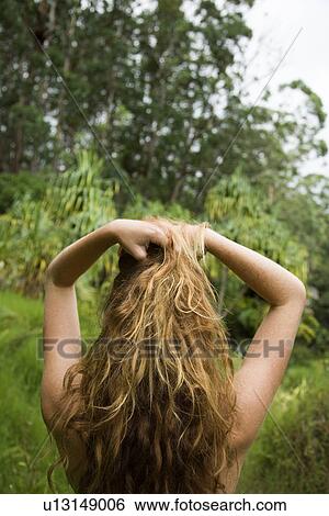 Back view of woman in lush forest holding up long wavy hair. View Large Photo Image Stock Photograph - Back view of woman in lush forest holding up long wavy hair.. Fotosearch