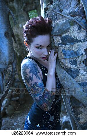 Blue-toned portrait of fearful looking tattooed Caucasian woman next to concrete wall View Large Photo Image Picture - Blue-toned portrait of fearful looking tattooed Caucasian woman next to concrete wall . Fotosearch