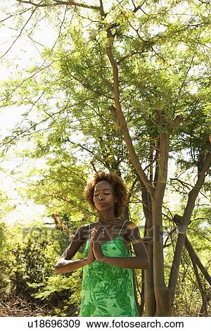 Stock Photo - Mid-adult Black female in woods meditating.. Fotosearch