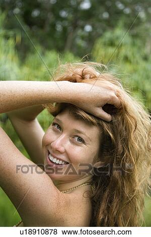 Stock Photo - Woman in lush forest holding up long wavy hair. Fotosearch