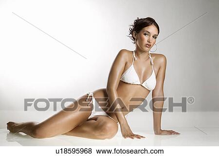 Stock Photo - Caucasian young adult woman in bikini sitting on floor and looking at viewer.. Fotosearch