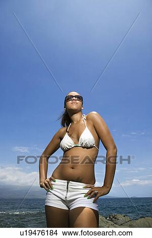 Multi ethnic young adult woman standing on beach in bikini. View Large Photo Image Picture - Multi ethnic young adult woman standing on beach in bikini.. Fotosearch