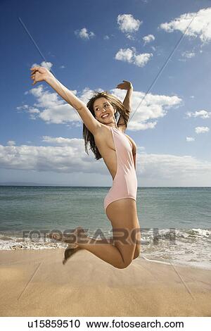 Pretty smiling young Caucasian woman in swimsuit jumping into air at beach View Large Photo Image Stock Image - Pretty smiling young Caucasian woman in swimsuit jumping into air at beach . Fotosearch