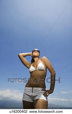 Stock Image - Woman standing on beach in bikini. Fotosearch
