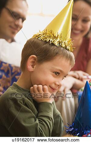 Stock Photo - Boy at birthday party looking to the side and smiling. Fotosearch