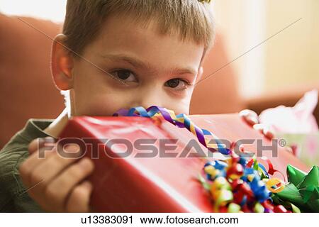 Boy holding gift up to face View Large Photo Image Stock Image - Boy holding gift up to face. Fotosearch