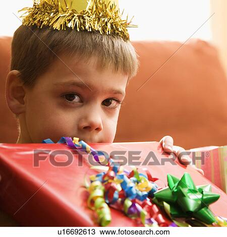 Stock Image - Boy holding gift up to face. Fotosearch