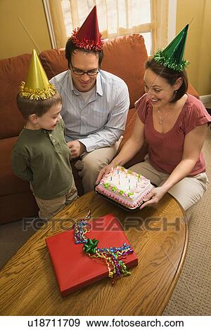 Boy in party hat with Birthday cake and family View Large Photo Image Stock Photo - Boy in party hat with Birthday cake and family. Fotosearch