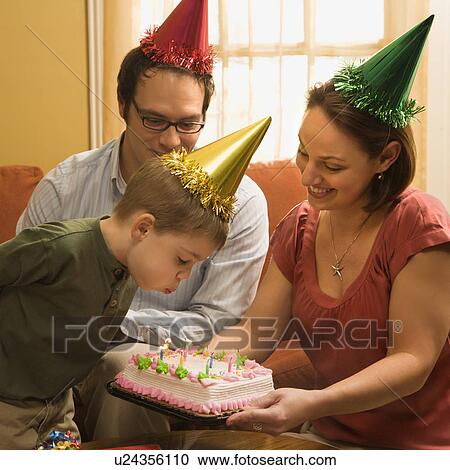 Caucasian boy in party hat blowing out candles on birthday cake with family watching. View Large Photo Image Stock Image - Caucasian boy in party hat blowing out candles on birthday cake with family watching.. Fotosearch