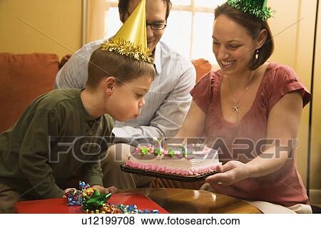 Caucasian boy in party hat blowing out candles on birthday cake with family watching. View Large Photo Image Stock Photo - Caucasian boy in party hat blowing out candles on birthday cake with family watching.. Fotosearch