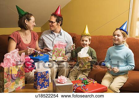 Picture - Caucasian family wearing party hats and celebrating a birthday party.. Fotosearch