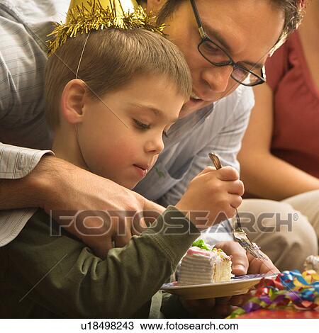Stock Image - Caucasian mid adult father helping son with birthday cake.. Fotosearch