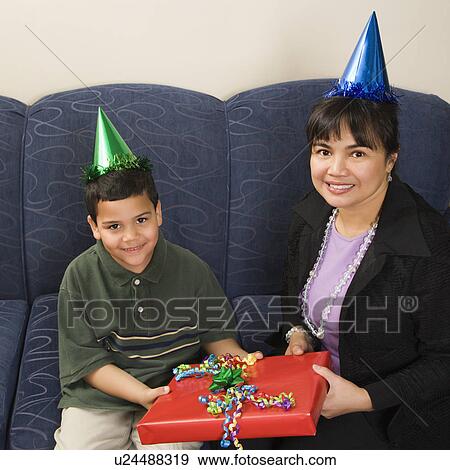 Stock Photo - Mother and son wearing party hats holding birthday presents smiling and looking at viewer. Fotosearch