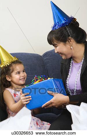 Mother giving daughter present at birthday party View Large Photo Image Stock Image - Mother giving daughter present at birthday party. Fotosearch