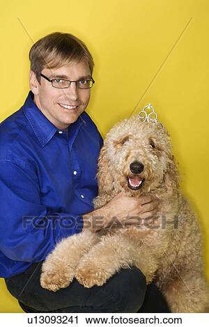 Stock Image - Man with Goldendoodle dog. Fotosearch