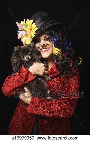 Stock Image - Woman holding black Pomeranian dog. Fotosearch