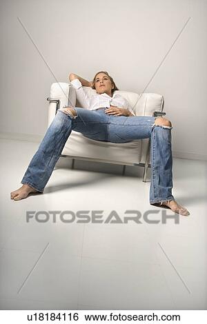 Stock Photograph - Woman in blue jeans lounging in chair.. Fotosearch