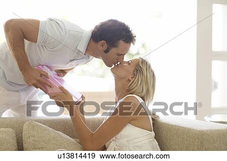 Stock Photo - Man giving present to woman and kissing on lips. Fotosearch
