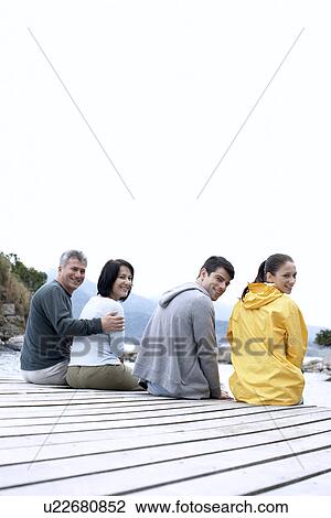 Mature and young couple sitting on jetty View Large Photo Image Stock Image - Mature and young couple sitting on jetty. Fotosearch