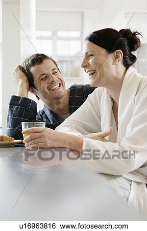 Mid adult couple laughing at breakfast table View Large Photo Image Stock Photograph - Mid adult couple laughing at breakfast table. Fotosearch