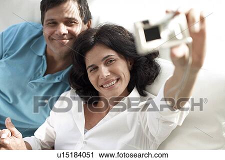 Mid adult couple photographing themselves View Large Photo Image Stock Image - Mid adult couple photographing themselves. Fotosearch