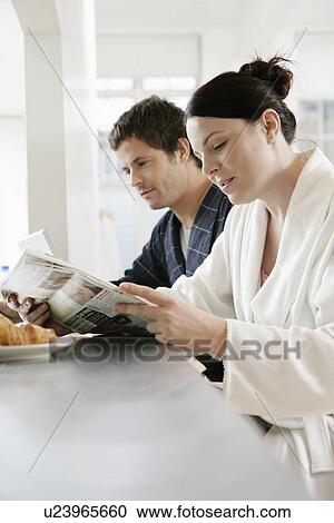 Stock Image - Mid adult couple reading newspaper at breakfast. Fotosearch