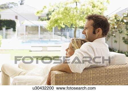 Mid adult couple relaxing on sofa and looking at garden View Large Photo Image Stock Image - Mid adult couple relaxing on sofa and looking at garden. Fotosearch