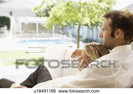 Mid adult couple relaxing on sofa and looking at garden View Large Photo Image Stock Photograph - Mid adult couple relaxing on sofa and looking at garden. Fotosearch