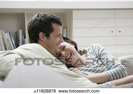 Stock Photo - Mid adult couple sitting on sofa. Fotosearch