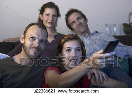 Stock Image - Two mid adult couples watching TV. Fotosearch