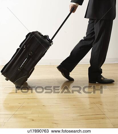 Stock Image - Businessman Pulling Wheeled Suitcase. Fotosearch