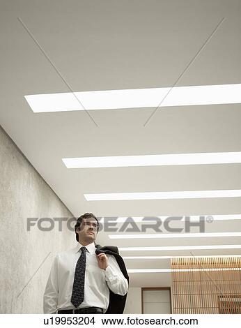 Businessman under strip lights (low angle view) View Large Photo Image Picture - Businessman under strip lights (low angle view). Fotosearch