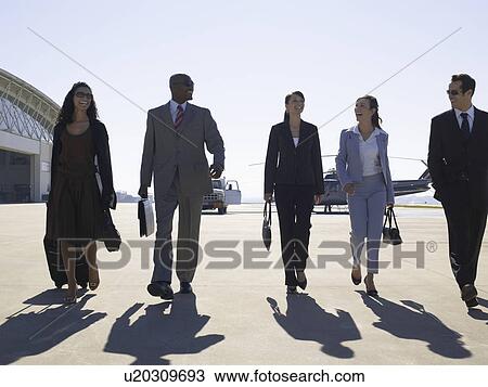 Stock Image - Five businesspeople walking at airport. Fotosearch